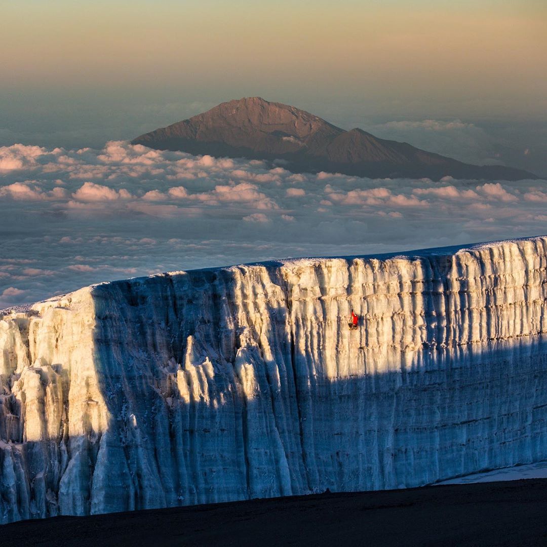 Photo by @christianpondella | On top of Africa, @realwillgadd climbing near the summit of Mount Kilimanjaro in Tanzania, Africa as Mt Meru sits above the clouds.